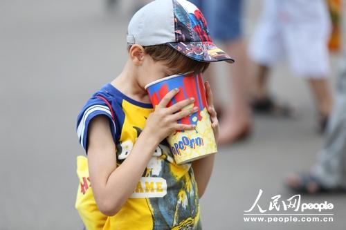 一个小男孩将脸埋进爆米花桶（人民网记者 刘旭摄）