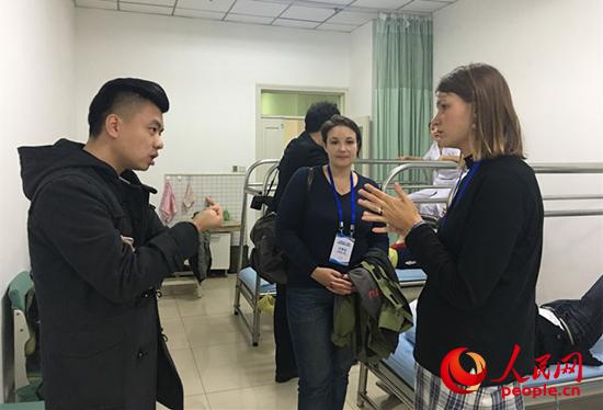 体验了踩跷按摩的俄罗斯记者卡兹洛娃·尤利娅表示，踩跷看起来很疼，但实际上很舒服。“肩部的酸痛感好多了”。图为卡兹洛娃与其他患者交流。